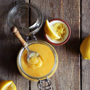 image of lemon curd in a glass jar with a spoon in it