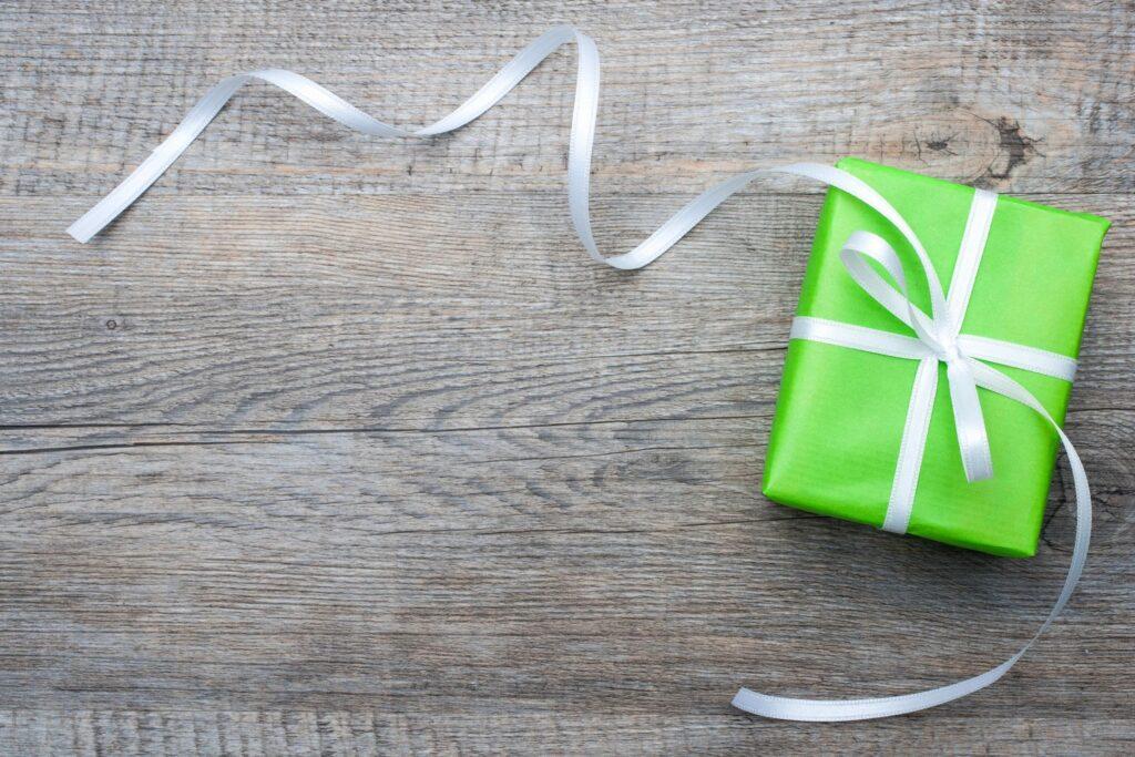 image of gift wrapped in green paper and white ribbon on wooden background for the edibles gift guide episode