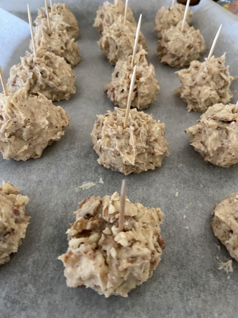 kentucky bourbon balls on a tray with toothpicks in them ready to be dipped in choclate