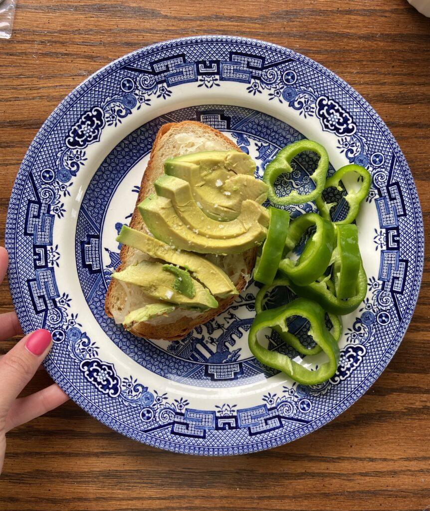 A plate with a slice of CBD infused avocado toast along with sliced green peppers on the side.