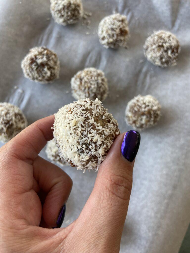 a close up photo of a cannabis infused coconut date balls with a tray of them in the background