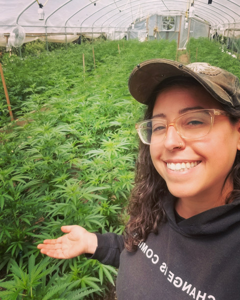 Amanda Breeze pictured wearing a ball cap with a cannabis grow in the back ground.