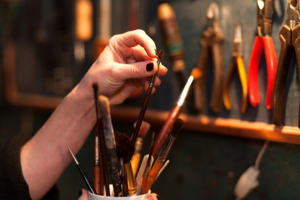 a hand taking a brush out of a cup of many paint brushes. for the puff, paint, play January challenge. 