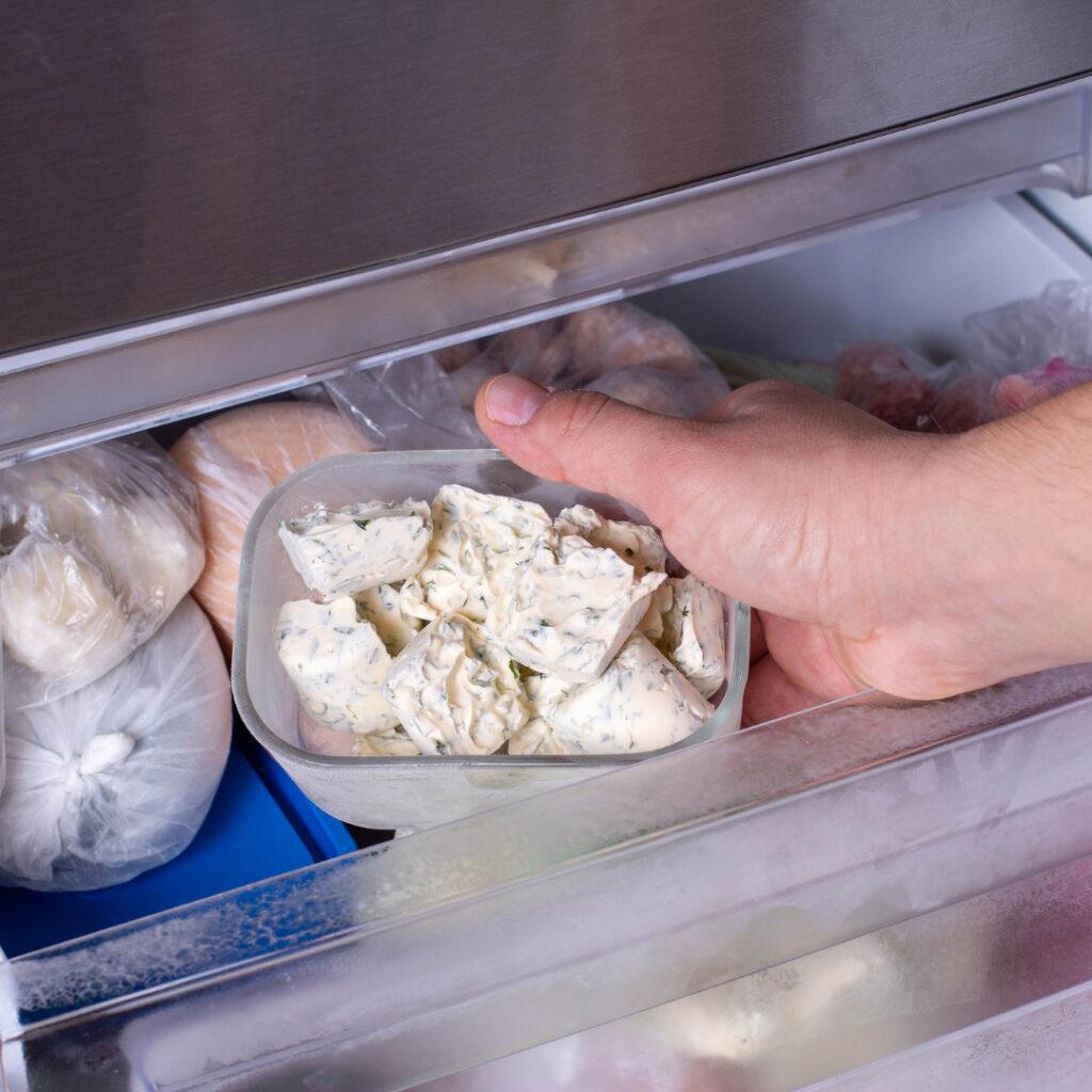 a dish of frozen butter cubes being put in a freezer drawer for the freezing edibles episode