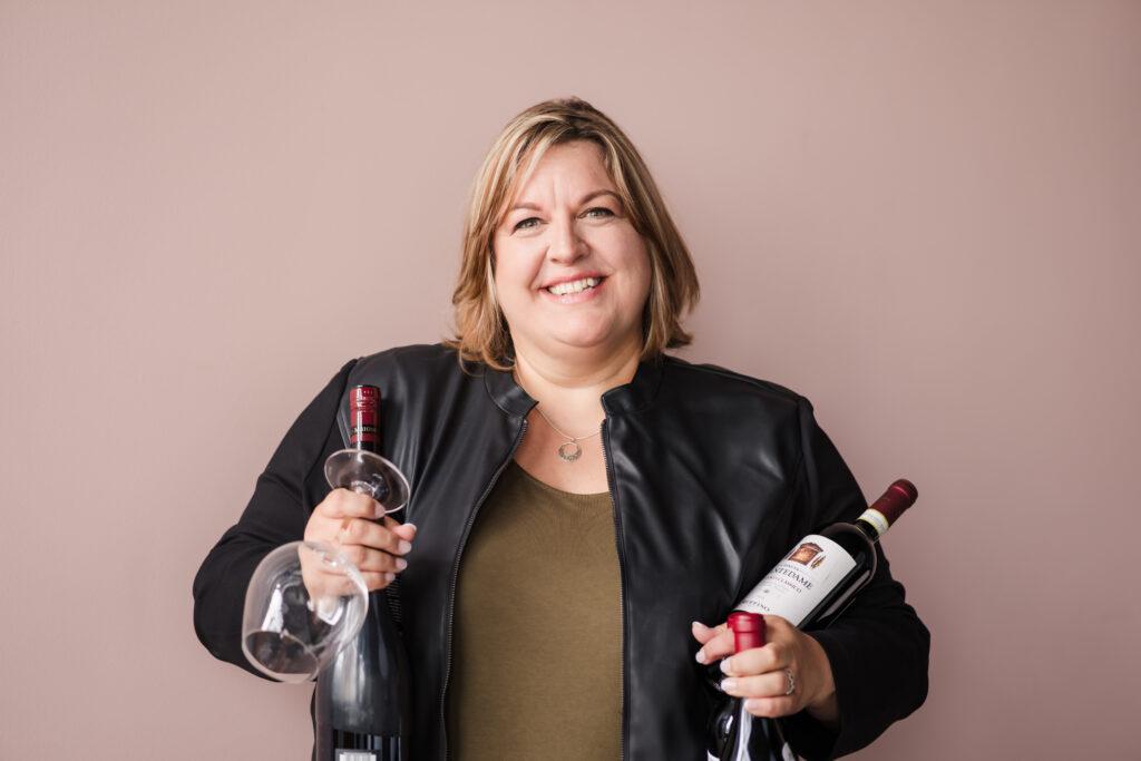 Photo of Jackie McAskill co-founder of Sheesh Hash Soda, holding bottles of wine in each hand.
